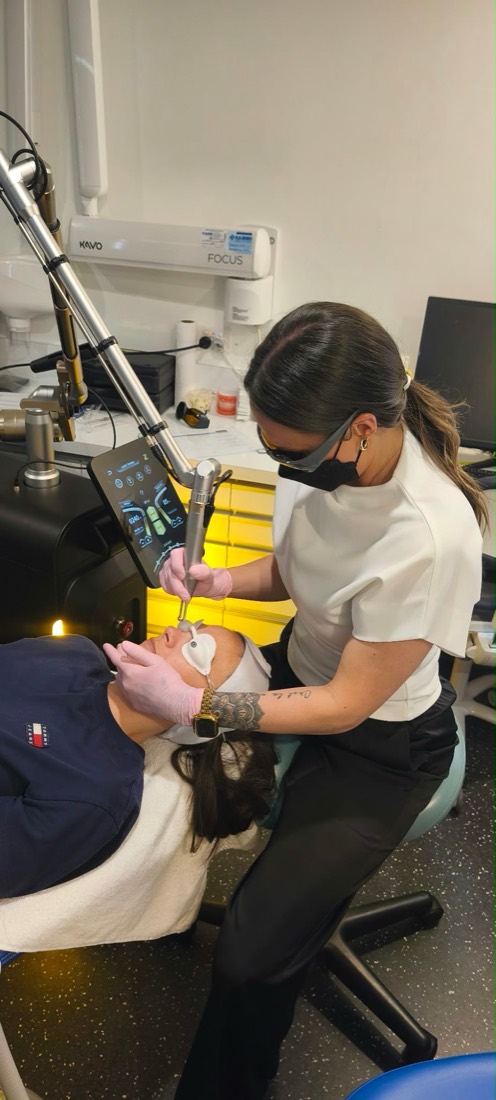 A carbon laser facial underway at The Laser Co., the client wearing protective eye shields while the laser handpiece passes over the skin.